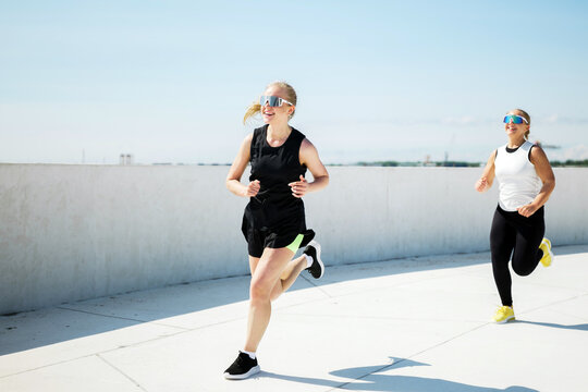 Women enjoying a sunny morning jog on a sleek outdoor track with clear blue skies