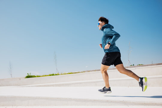 Man jogging on a sunny day in an outdoor park setting, enjoying fitness and nature
