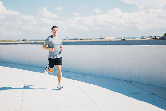 Running along the waterfront path under a clear blue sky in a vibrant city