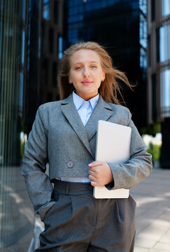 Business professional standing confidently in a modern urban setting with sleek glass buildings around