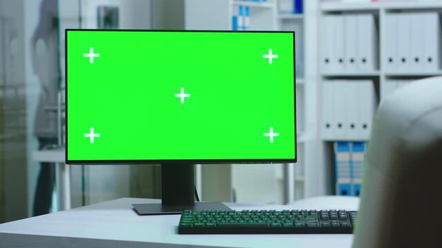 dolly shot frames a green screen computer in a clinic office while medical staff remain behind, combining healthcare context with flexible mockup space.