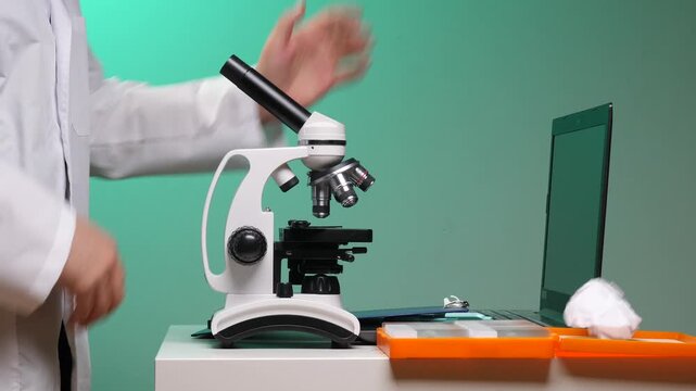 Scientist in lab coat cleaning a microscope objective lens by hand, prepping precise equipment for biology research, diagnostics and experiments in a professional laboratory setting