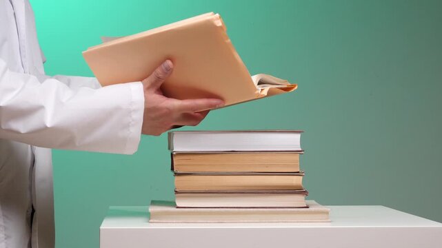 Medical professional in a lab coat holding a manila folder of documents and research papers beside a stack of medical textbooks, symbolizing study, research, and expertise in medicine