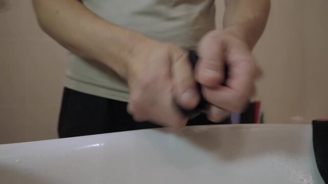 Close-up of adult male hands washing black sock with careful, controlled motion