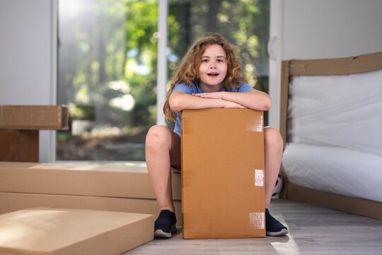Moving house with cardboard boxes. Moving house child in playroom. Moving house packing boxes indoors. Moving house family relocation concept.