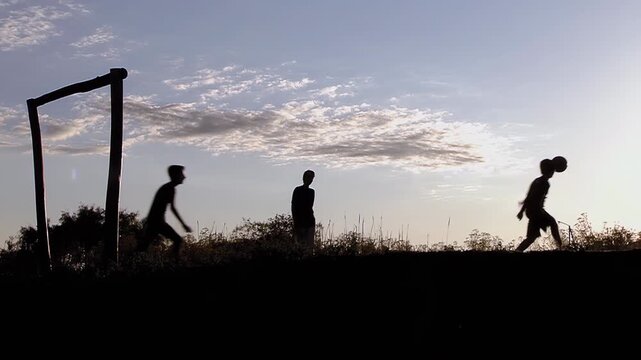 Slow Motion Silhouette of Kids Playing Football on Countryside Field During Golden Hour - 4K
