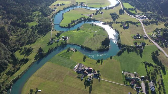 Curving river through green fields and meadows with isolated houses, aerial view, mountain valley with meandering Stryneelva River, Stryn, Vestland, Norway
