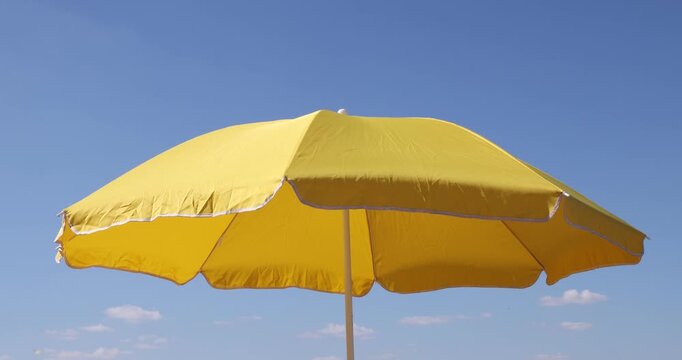 Yellow beach umbrella under blue sky, closeup