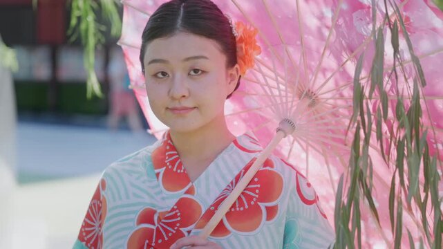 A young Japanese woman wearing a traditional kimono and holding a pink parasol in Senso-ji Temple, Tokyo, Japan, during a cultural celebration day.