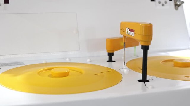 White laboratory machine holds several yellow reagent containers on display, Close view of sample vessels and probes at a medical exhibition