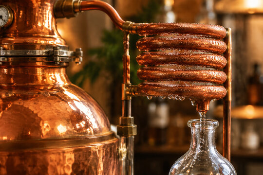 Polished copper distiller with condensation on its coiled tube.