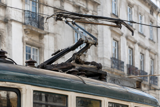 Close-up of a pantograph contacting overhead wires on a vintage tram.