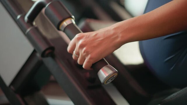 Close up view shows person forearm as they grip handle of gym equipment likely for strength or fitness exercises. focus remains on hand and arm movement with blurred background indicating