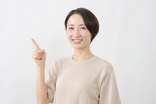 左を指差す笑顔の女性　ミドルエイジ　白背景