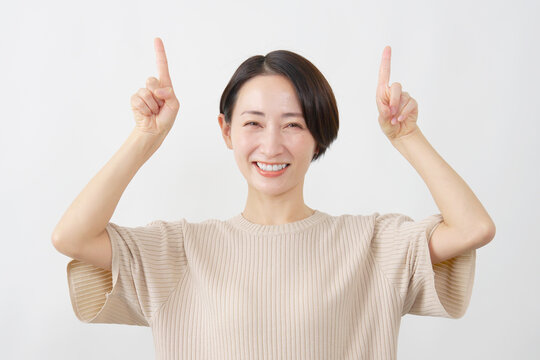 両手で上を指し示す女性　ミドルエイジ　白背.