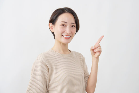 右を指差す笑顔の女性　ミドルエイジ　白背景