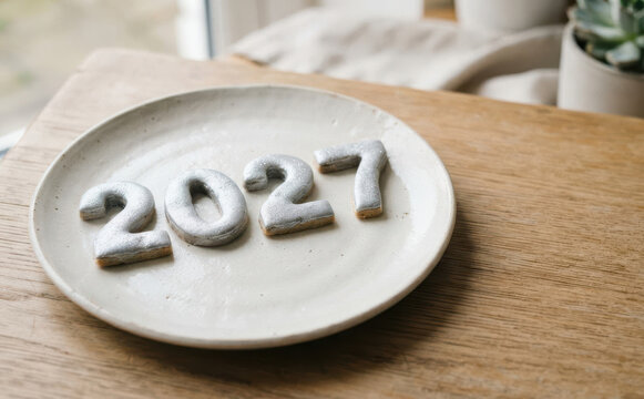 Silver numbers forming 2027 on a plate on a wooden table representing future years and upcoming events