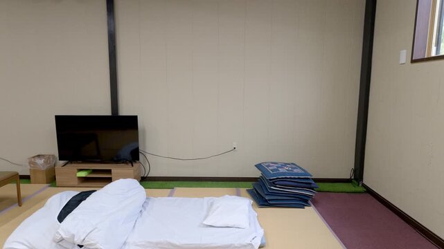 和室の畳の上に敷かれた一組の白い布団（合宿所・民宿・寝具）