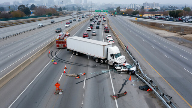 A semi truck and a police cruiser involved in a traffic accident on a freeway with accident multi lane fire rescue vehicle lane highway near white semi safety