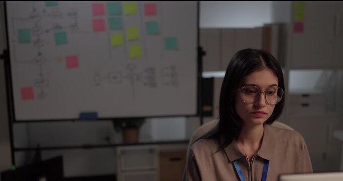 Woman software developer planning sprint on whiteboard flowchart with sticky notes in office