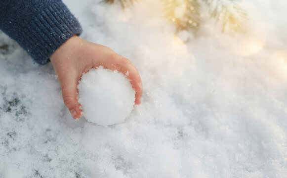 Child making snowball in winter snow outdoors, close up on little hands holding snow ball for fun seasonal children activity