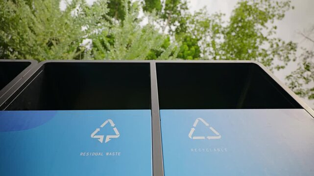 A transparent plastic bottle is thrown into recycling bin. Waste sorting. A garbage bin with waste sorting symbol. Garbage collection and cleanup.