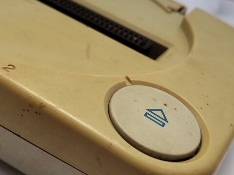 Macro shot of a dirty eject button on a vintage, yellowed knock-off 8-bit retro video game console