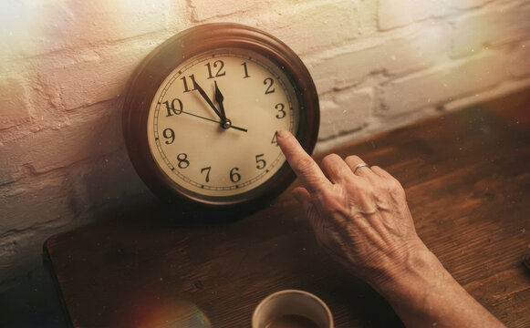 Elderly woman hand touching wall clock face counting time concept of aging and mortality