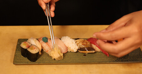 Chef Arranging Assorted Nigiri and Maki Sushi on Ceramic Plate © blueringmedia