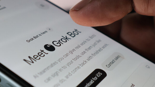 Close up hand interaction on mobile screen with meet grok bot text and download for ios button for ai task automation.