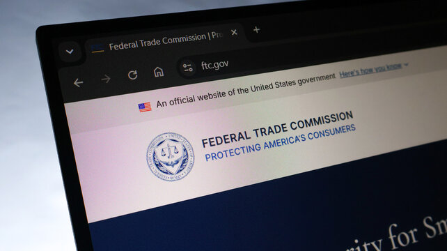 A laptop screen shows the official website of the Federal Trade Commission, featuring its seal and motto.