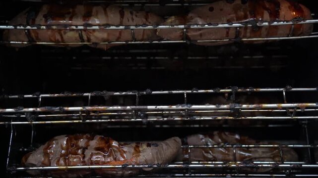 Rows of sweet potatoes cooking evenly on roller grill machine.