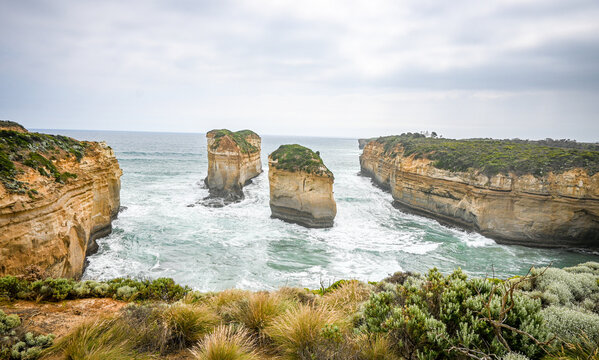 beautiful photo of a twelve apostles two beautiful cliffs standing strong in the ocean in cloudy weather