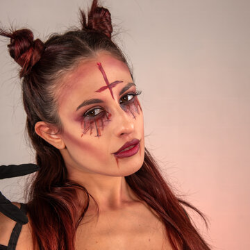 Woman portraying devilish character with inverted cross makeup