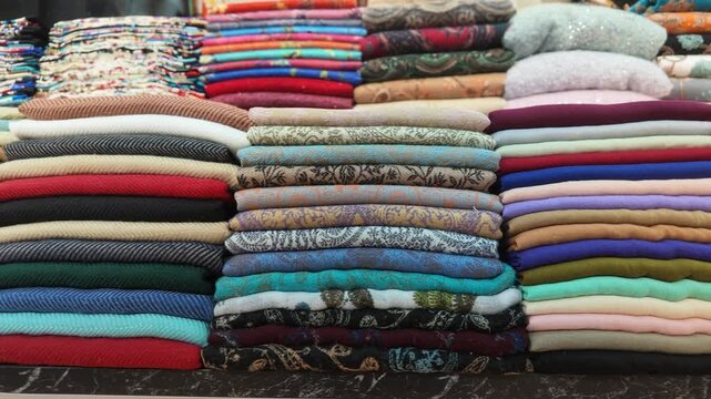 Colorful fabric rolls are stacked neatly in a marketplace display