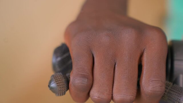 Close up shows firm steady grasp by adult human hand holding two textured handles. skin detail is clear with no significant movement or change in lighting
