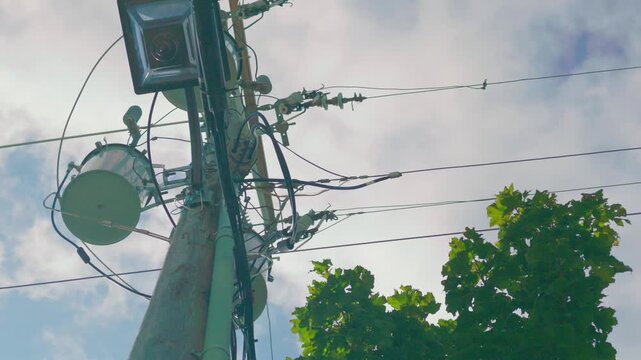 Three Phase Pole Mounted Transformer Bank with Street Light Under Cloudy Sky