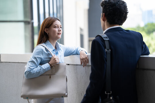 Two colleagues converse outdoors near a building exterior, sharing ideas and building professional trust during a work break in the urban area.