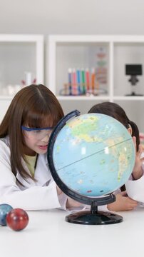Elementary School Girls in Lab Coats Studying World Globe