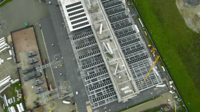 Large scale data center is under construction with industrial HVAC systems and cooling units being installed on the rooftop by cranes, showing the development of modern digital infrastructure