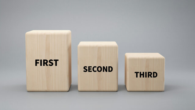 Three wooden blocks of varying heights labeled first second and third on a gray background with different heights arranged arranged row words third printed them order
