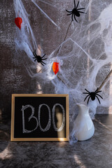 Blackboard with text BOO on decorative background of Halloween still life. Atmospheric Halloween concept designed for seasonal greetings classic spooky decorations to symbolize mystery celebration © anna.stasiia