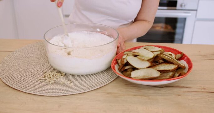 Baker occupation. Mixing dough. Female hand stirring flour batter at home kitchen modern workplace preparing dessert with sliced pear.