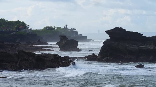 Oceanfront Sacred Site Exploration. Excursion To Holy Site Amid Crashing Waves And Dark Skies. Exploring Revered Religious Landmark Situated Along Tumultuous Ocean Shoreline Tanah Lot, Bali