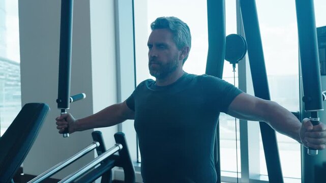 Sporty man training on chest fly machine in gym. Chest fly on pec deck machine. Pec muscles workout. Chest fly machine workout. Strong sportsman training at pec fly machine in gym. Strength training