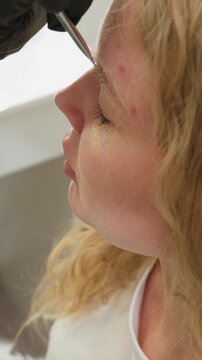 Close up side profile shows person undergoing precise facial grooming procedure. gloved hand performs eyebrow threading on person face with visible detail of skin texture and treatment area