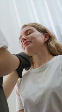 Close up view of woman receiving eyebrow threading service. Practitioner wearing black gloves performs precise manual technique on client face focusing on eye area. Indoor setting with soft
