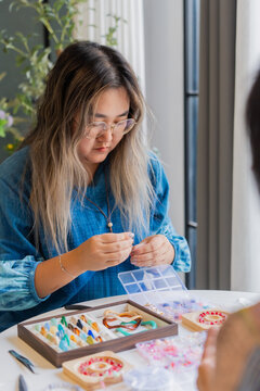 Two Asian woman making handcrafted jewelry together at home