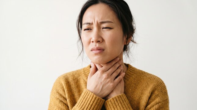 Close-up of a woman with a sore throat, holding her neck with a pained expression, feeling unwell and sick with a cold or flu.