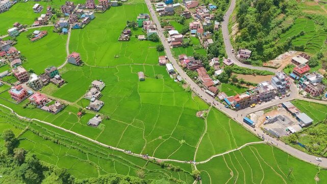 Aerial view of houses standing precariously at the eroded edge of a mud-filled riverbed after a devastating flash flood in a Nepal mountain valley